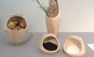 Wooden bowls containing vegetables and grains, and a vase with flowers in it.