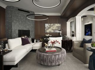 A living room with a large white sofa, a large upholstered coffee table, and modern circular light fixtures