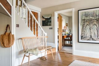 hallway with white stair spindles and walls and ercol bench seat with view to study