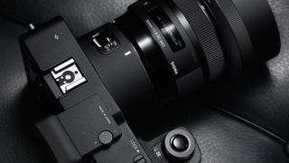 Sigma lens attached to mirrorless camera on dark gray background