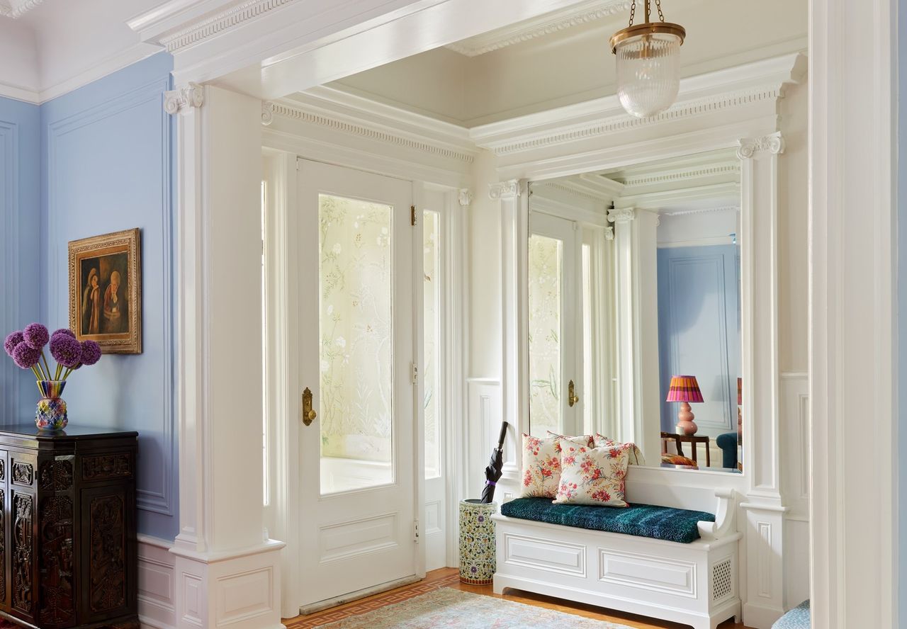 An entryway with a wallpaper, a cozy seating and white walls