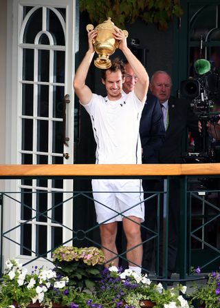 Andy Murray parades the trophy on a centre court balcony after winning the men's singles final against Milos Raonic on day thirteen of the Wimbledon Championships at the All England Lawn Tennis and Croquet Club, Wimbledon.