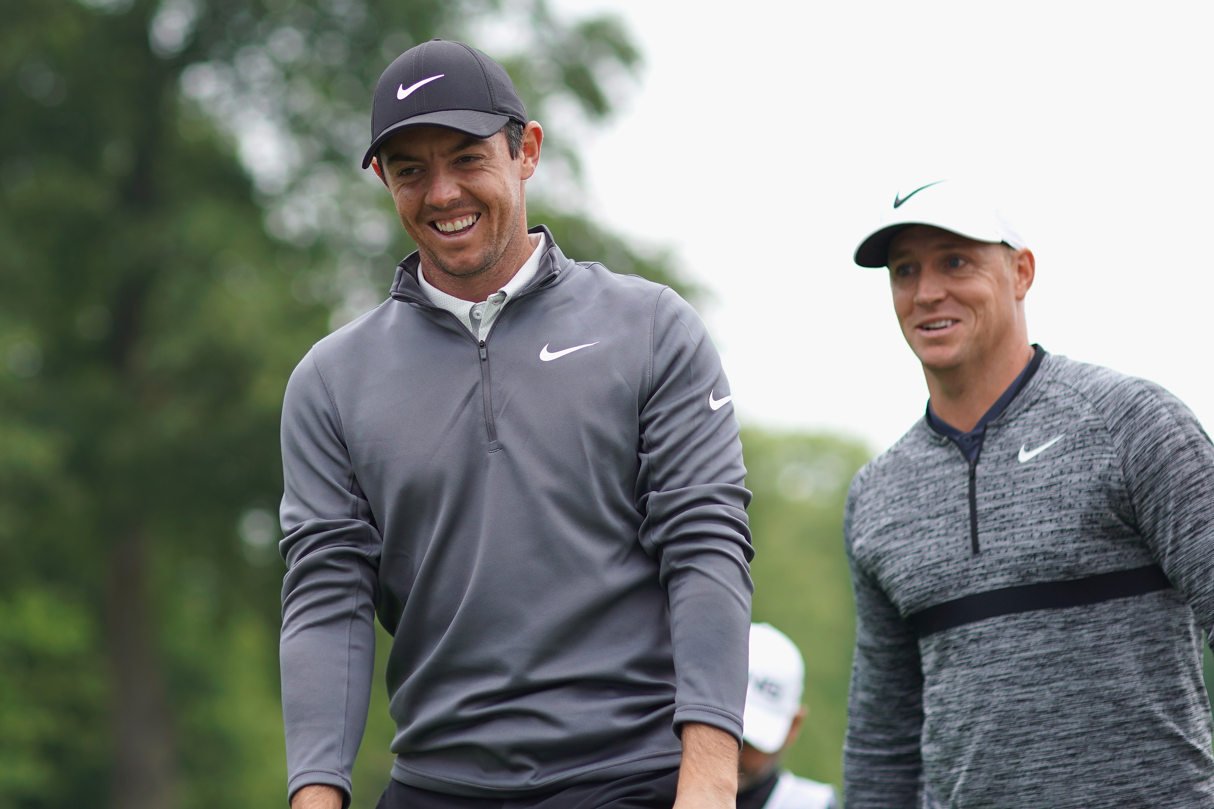 Rory McIlroy smiling with Alex Noren pictured behind him