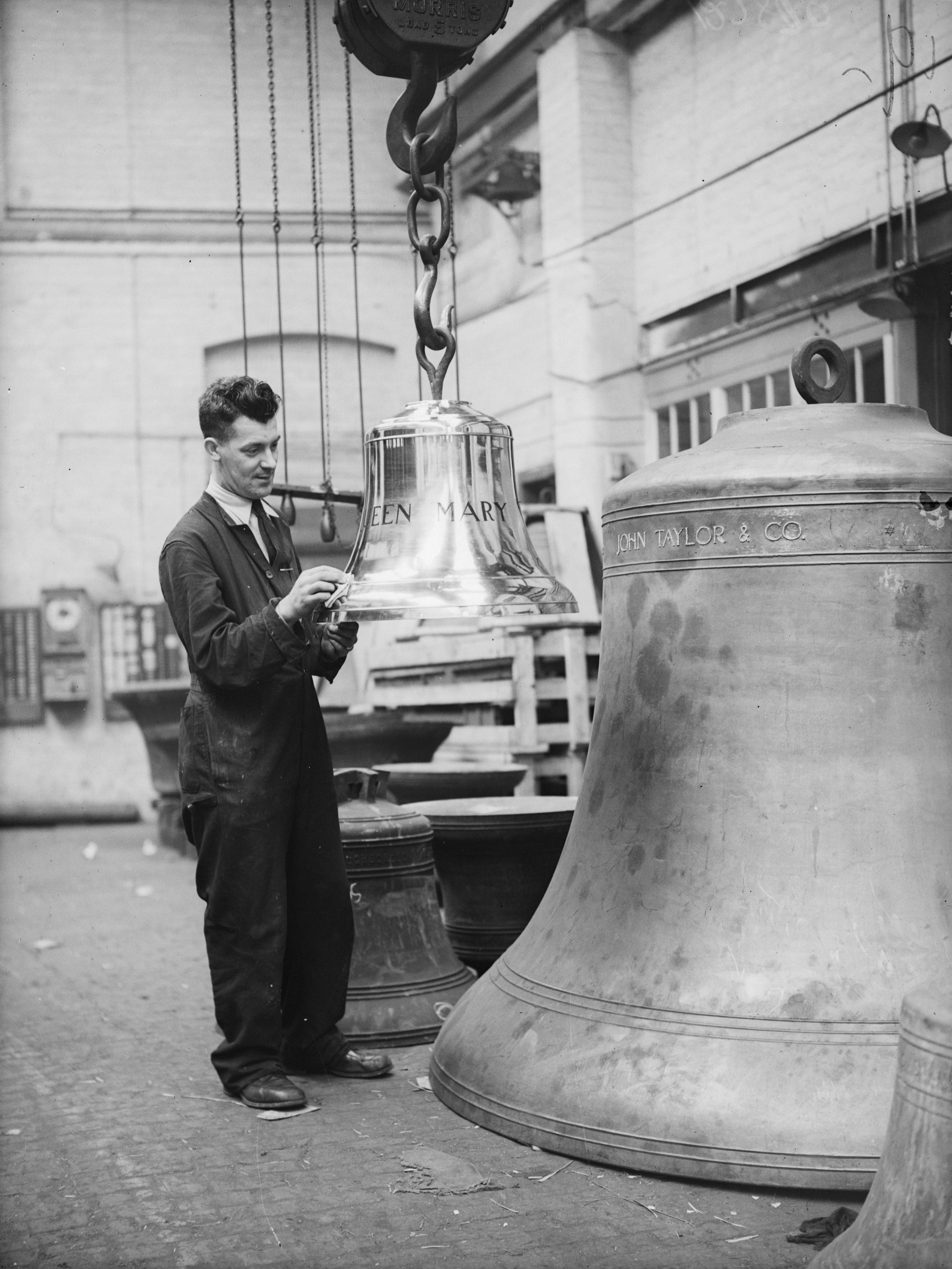 A workman at Taylor's bell foundry in Loughborough, with the smallest and the largest of the three ship's bells built for the liner, Queen Mary.