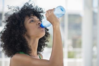 Woman drinking water from a bottle, after searching for 'why am I not losing weight'