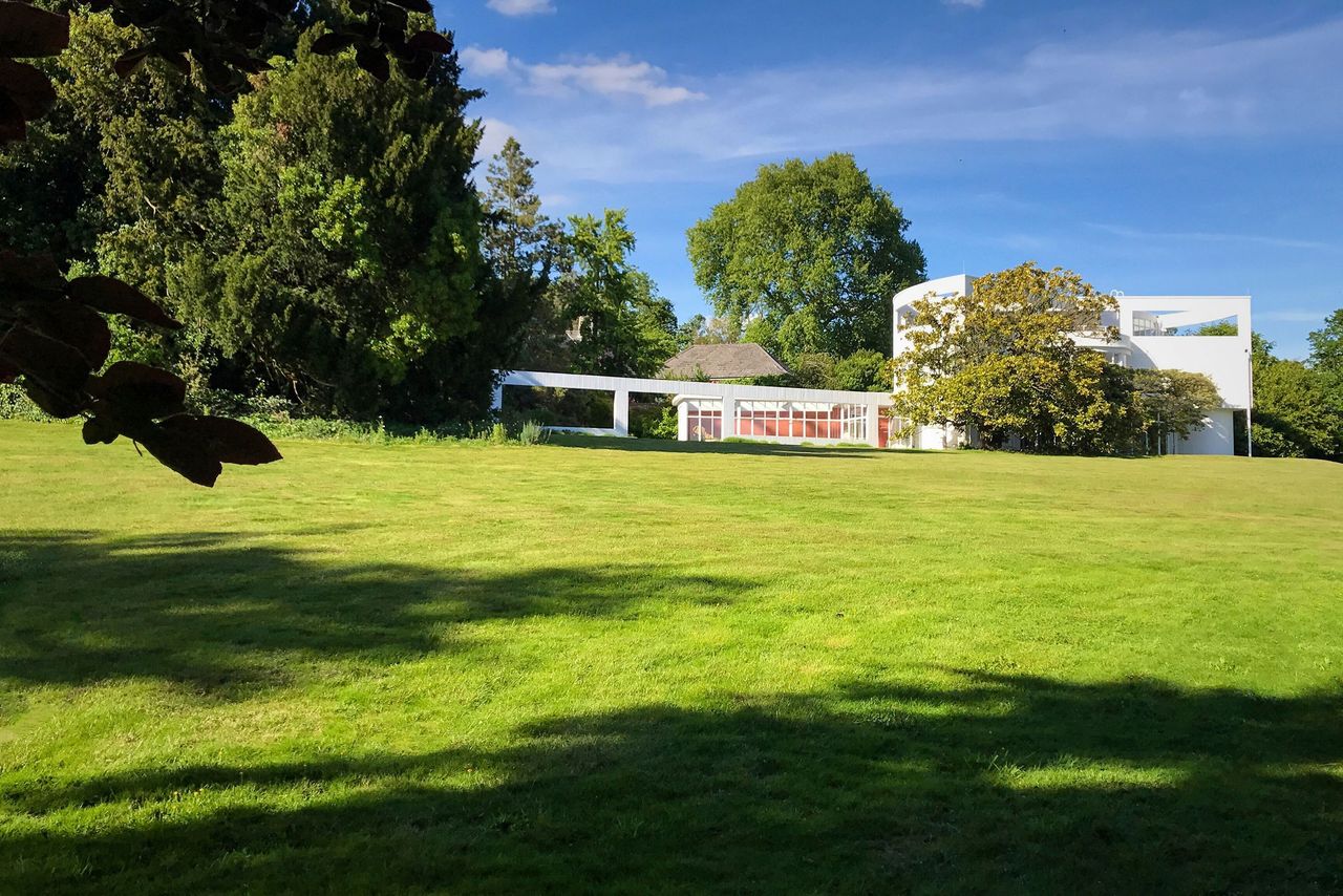 The front garden shows a large grass lawn and trees around the boundaries of the home
