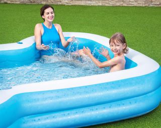 woman and child in a paddling pool on a lawn