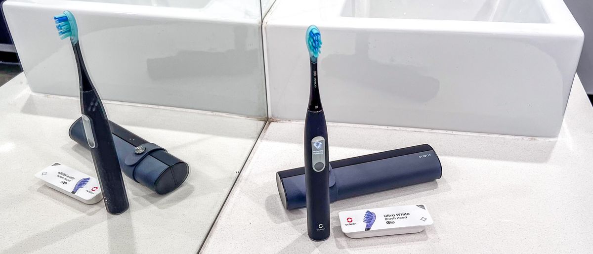 The Oclean X Ultra S electric toothbrush standing on a bathroom counter beside its travel case and replacement brush head