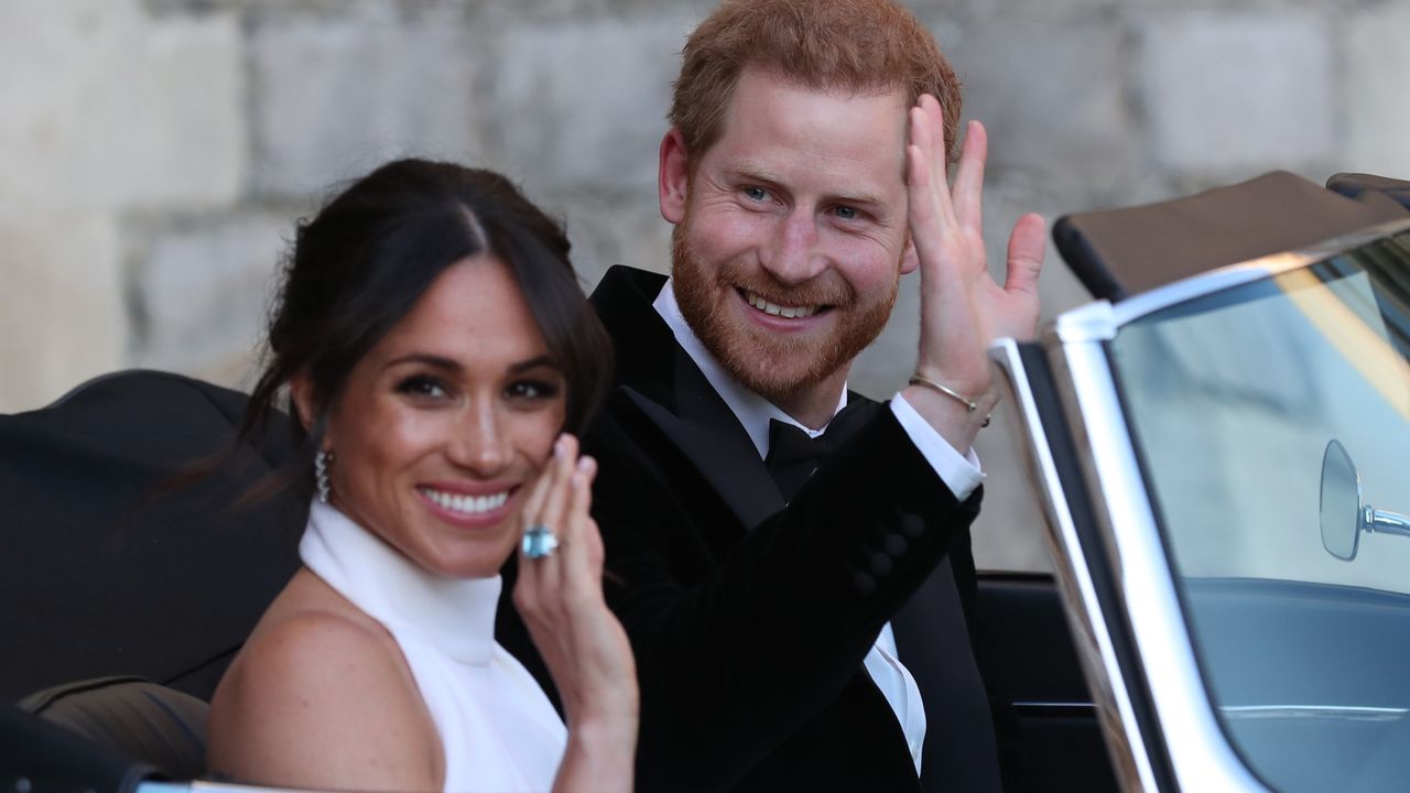 Duchess of Sussex and Prince Harry, Duke of Sussex wave as they leave Windsor Castle after their wedding to attend an evening reception at Frogmore House