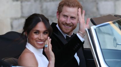 Duchess of Sussex and Prince Harry, Duke of Sussex wave as they leave Windsor Castle after their wedding to attend an evening reception at Frogmore House