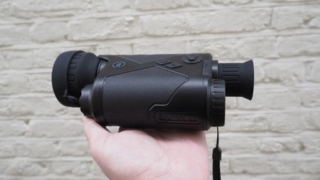 Bushnell Equinox Z2 6x50 Night Vision Monocular held in a hand against a white wall