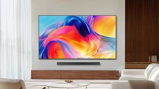 The Samsung M70H Mini-LED TV displaying colorful, abstract imagery from a wall-mounted position in a contemporary, well-lit living room