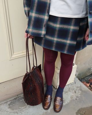 Fashion influencer @meganellaby wearing a chic winter outfit styled with 2024/2025's burgundy tights trend.