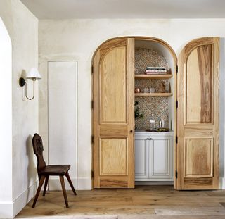 home bar concealed behind an arched wooden door