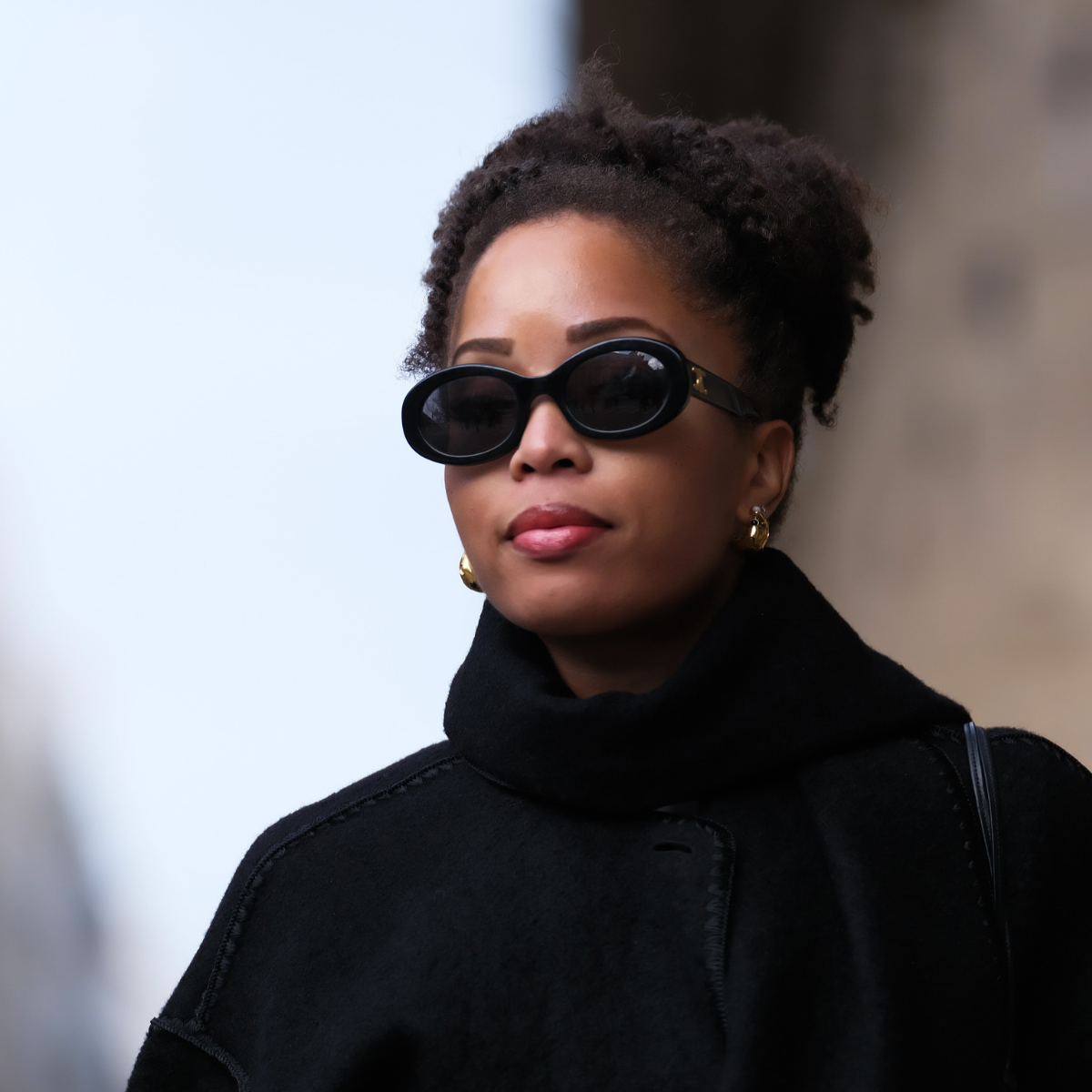 Hyperpigmentation in darker skin tones: Ellie Delphine wears Celine sunglasses, a black oversized wool scarf, a black coat from Toteme, a heart shaped bag from Alaia, during a street style fashion photo session, on November 06, 2023 in Paris, France