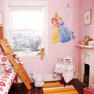 pink children's bedroom with fire place and floorboards