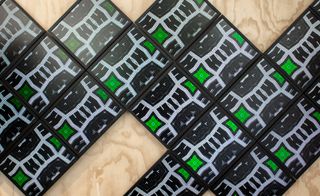 Black, grey and green patterned squares on a wooden surface.