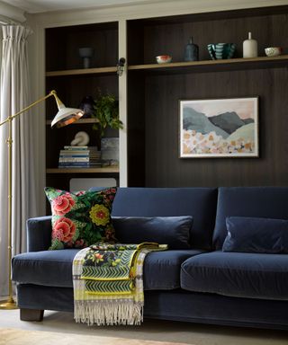 navy sofa with dark wood and light framed built in shelving unit behind