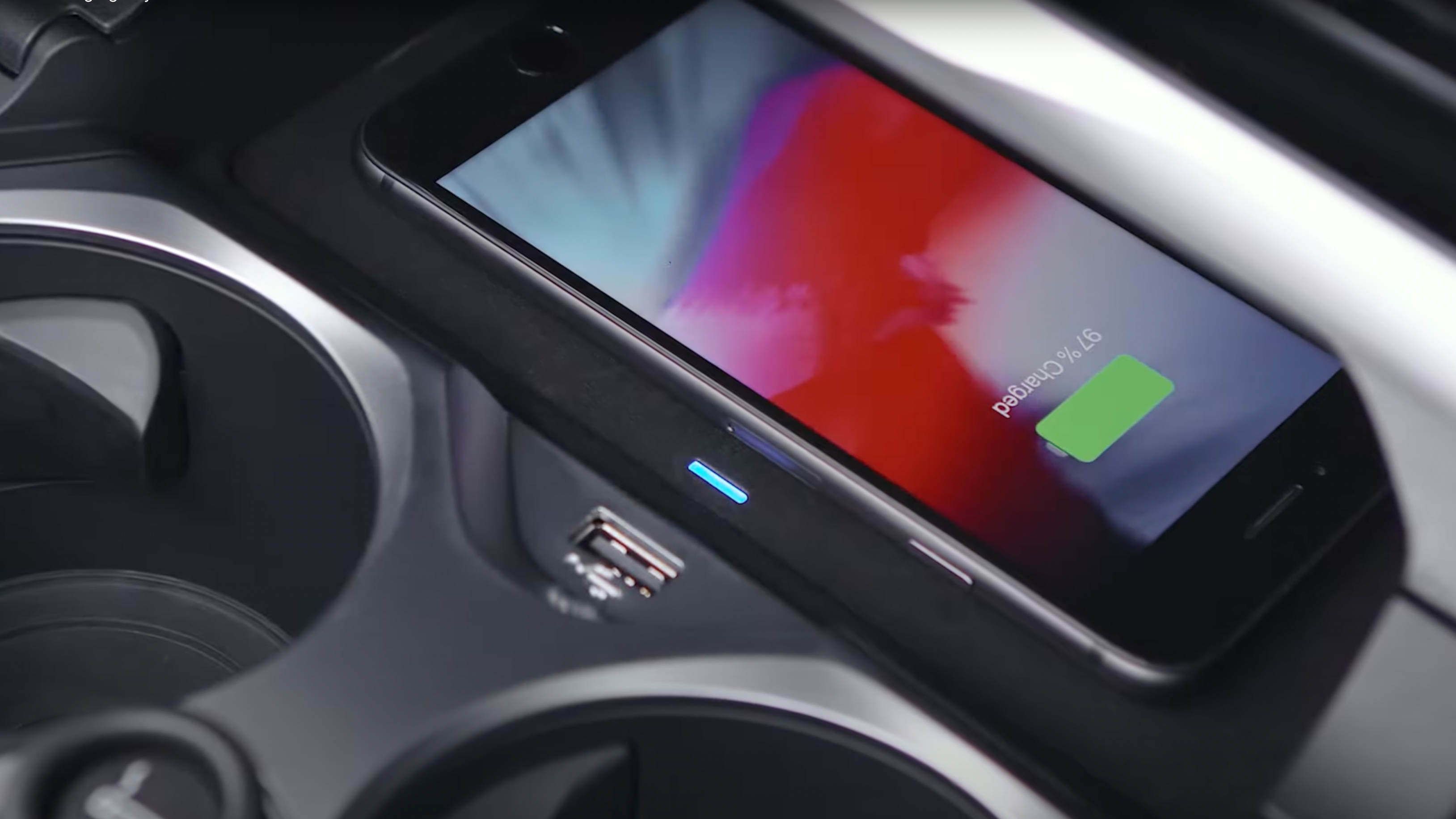 Un socle de recharge sans fil dans une BMW en train de recharger un iPhone