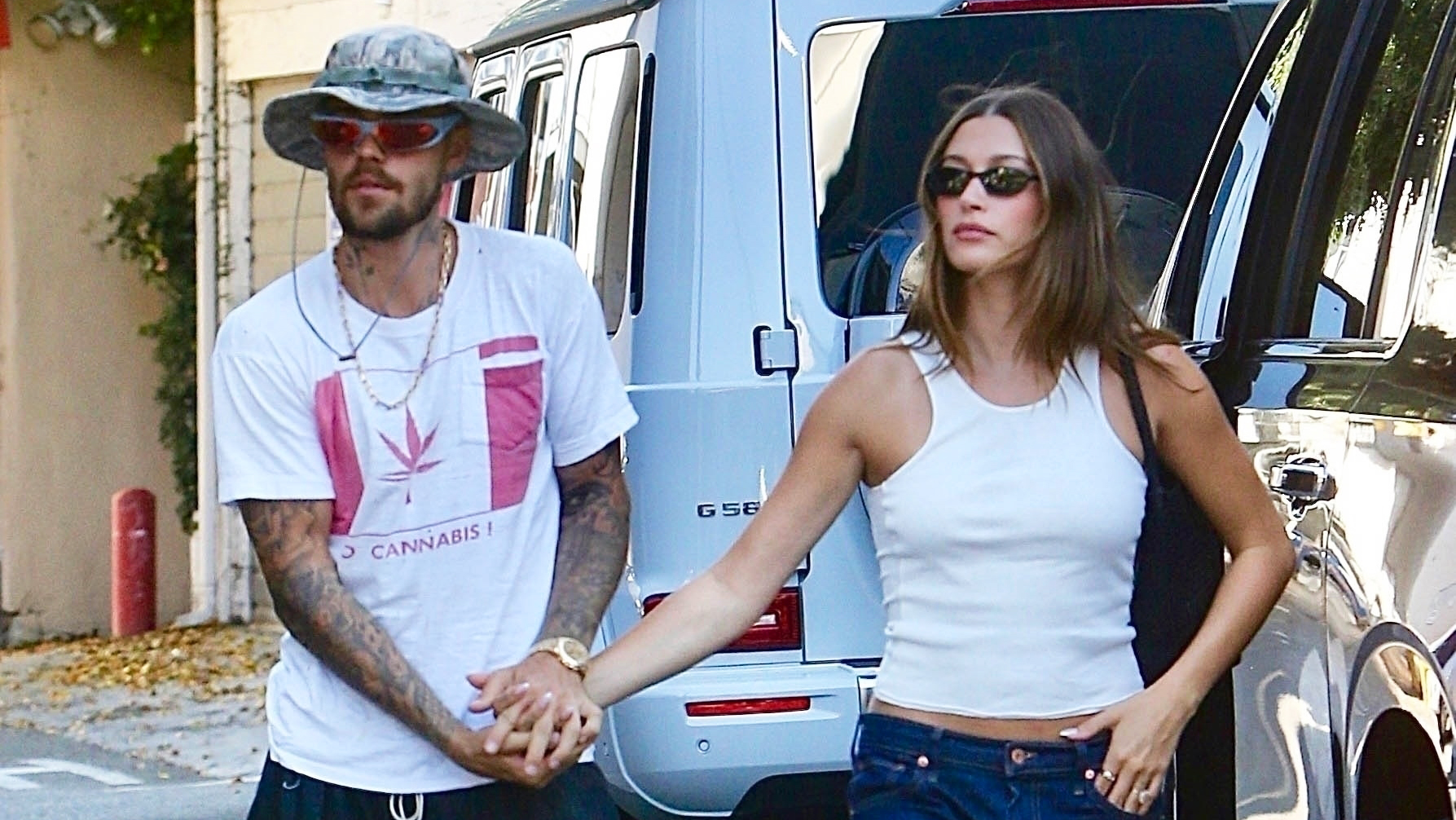 Hailey Bieber wearing a white tank top, dark denim Gap jeans, and The Row flip-flops