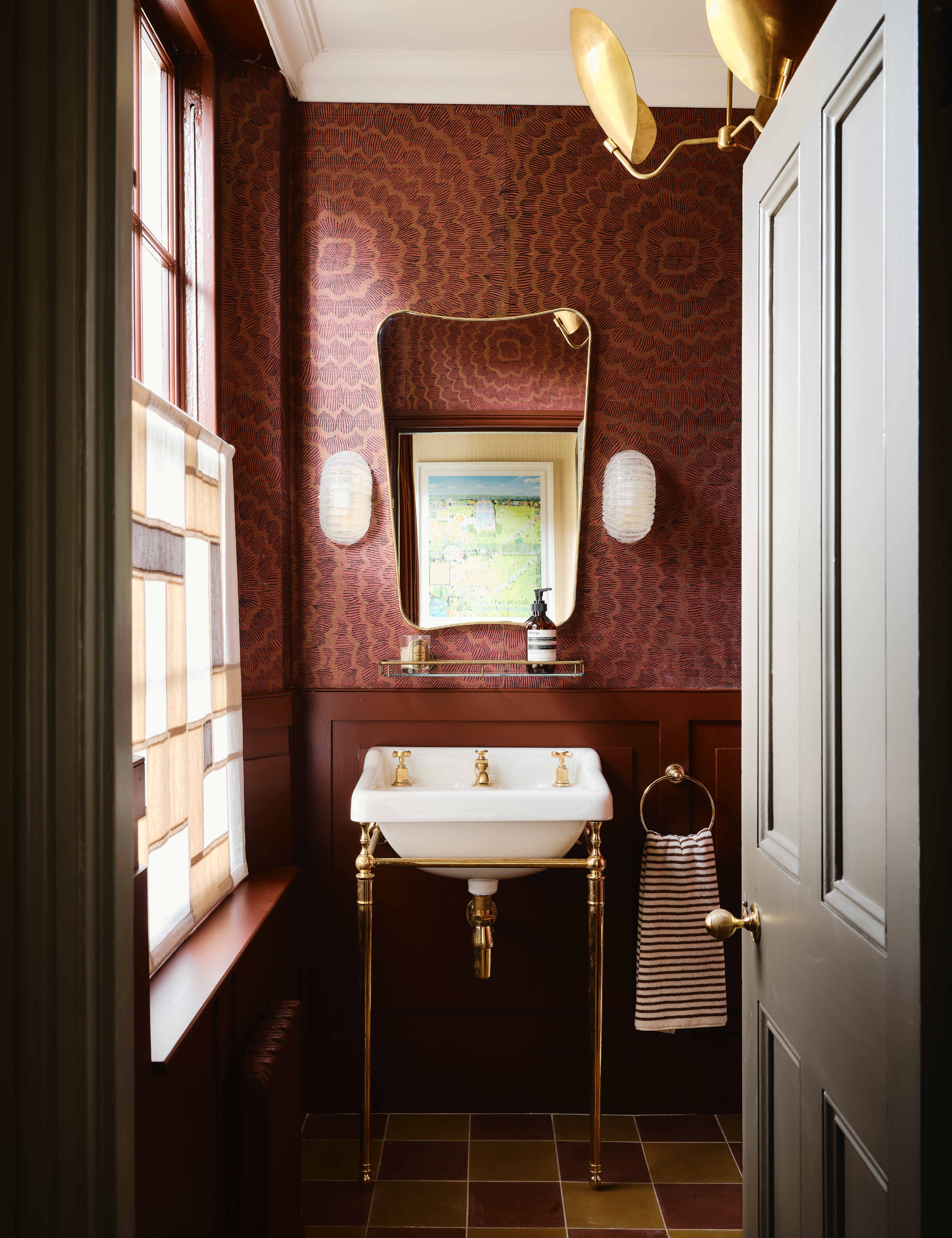Small oxblood bathroom featuring brass accents