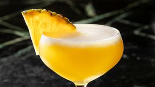 side shot of a pineapple martini garnished with a pineapple wedge