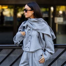 woman wearing grey ensemble, black sunglasses looking off to the side
