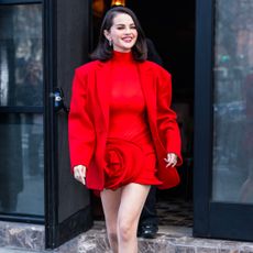 Selena Gomez wearing a lob hairstyle and a red suit smiling for the camera