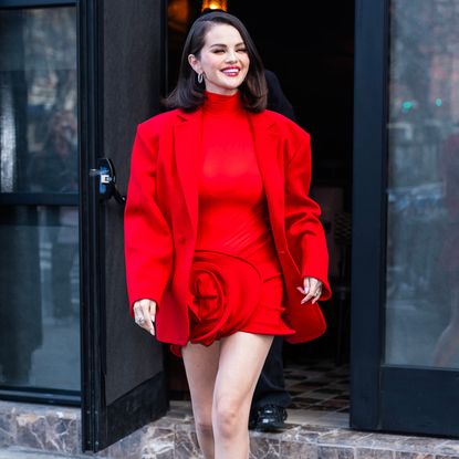 Selena Gomez wearing a lob hairstyle and a red suit smiling for the camera