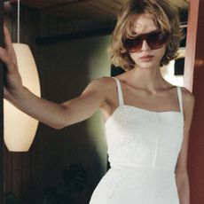 A Zara model wearing oversize sunglasses and a white sundress.