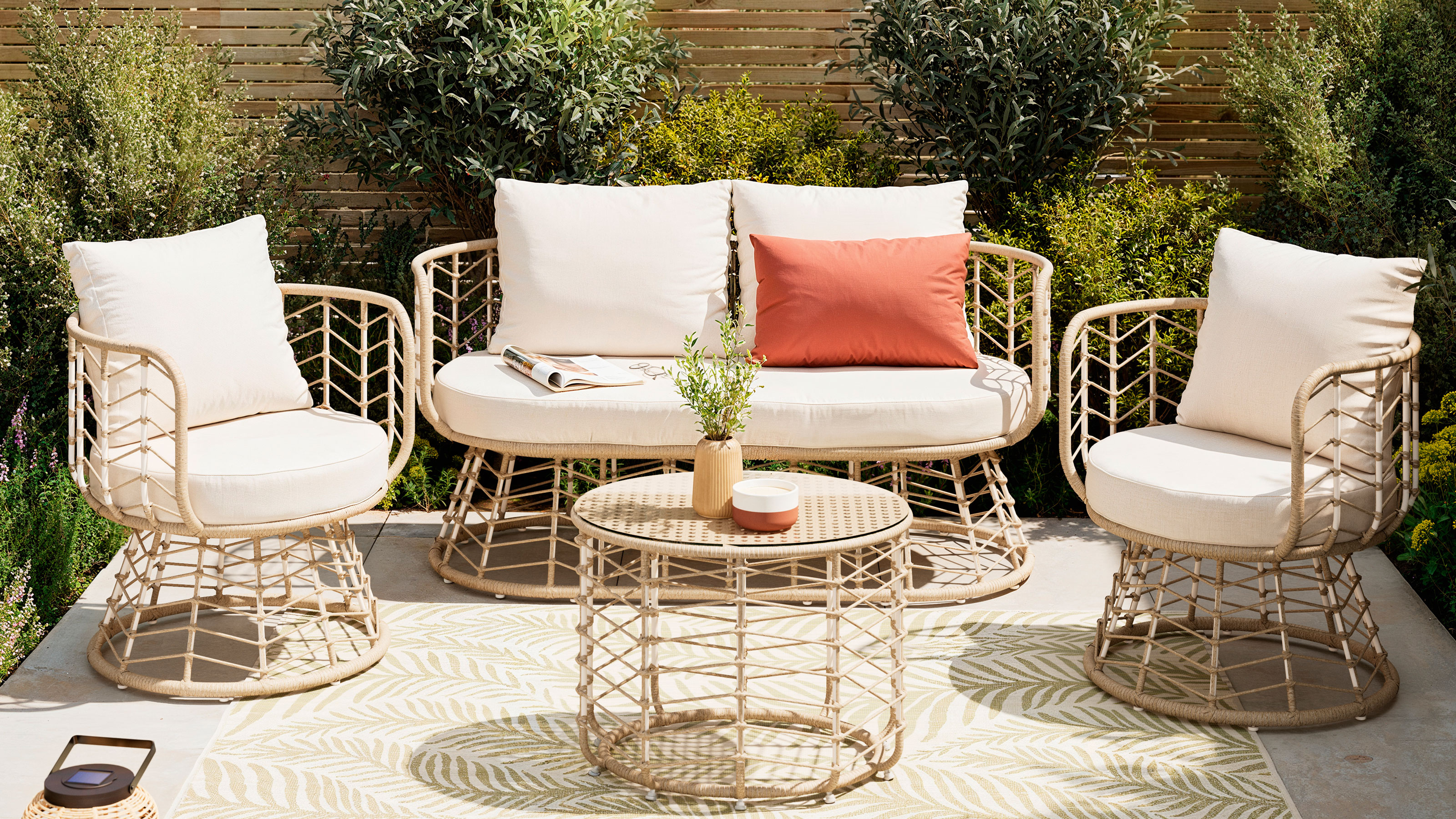 Patio set with beige cushions and coffee table on small patio with wooden fence