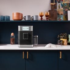 a navy blue kitchen with white worktop and a Kitchen Aid coffee amchine