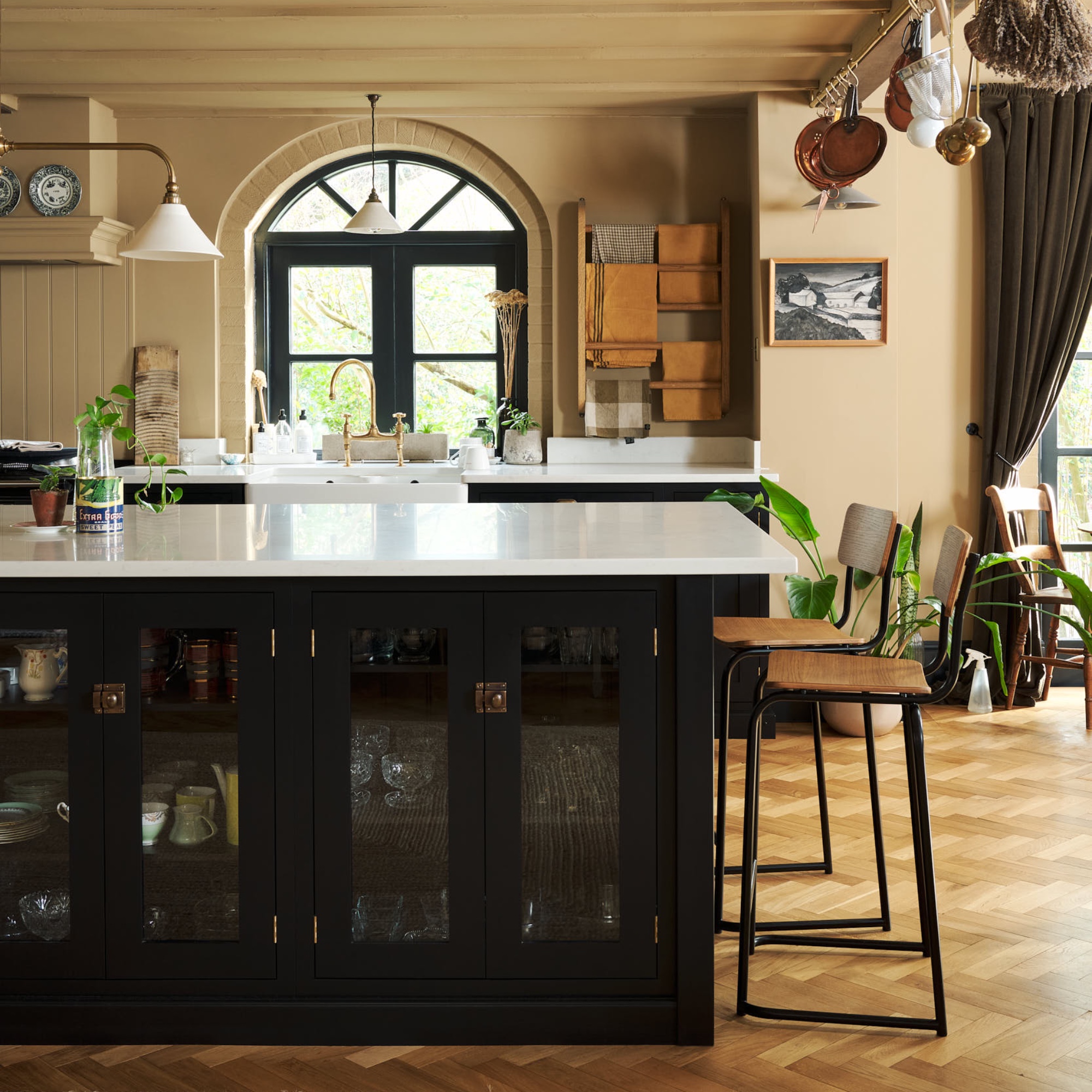 black and ochre kitchen with parquet flooring, white worktops, bar stools