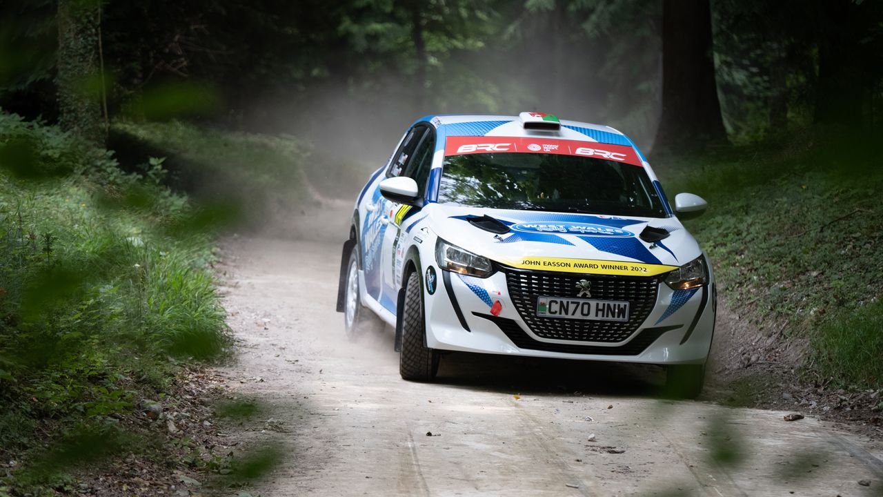 A rally car turning the corner of a race track at Goodwood
