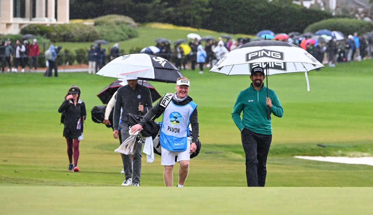 Matthieu Pavon, his caddie and Keegan Bradley walk up to the 18th green at Pebble Beach holding umbrellas 