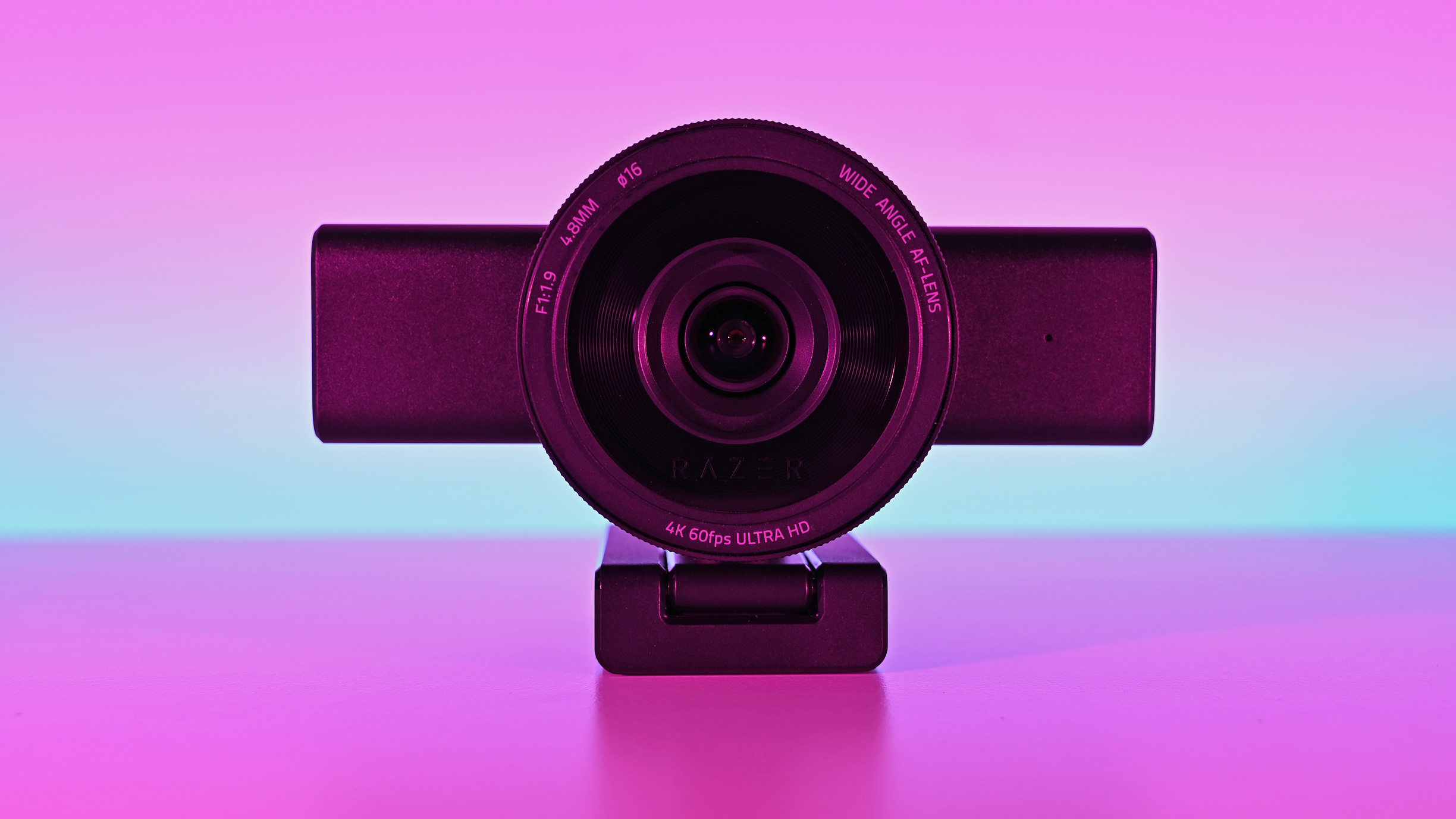Front view of the Razer Kiyo V2 Pro webcam on its monitor stand against a pink-and-blue gradient backdrop.
