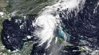 a spiral-shaped white cloud swirls above the southeastern united states as seen by a satellite