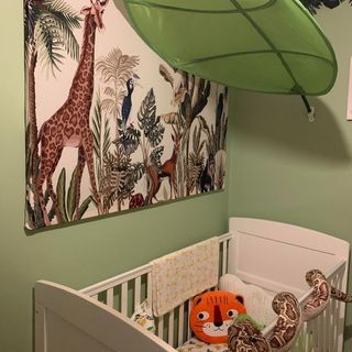 Nursery with green walls, white cot and zoo painting on the wall
