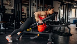 Woman performs incline row with kettlebells