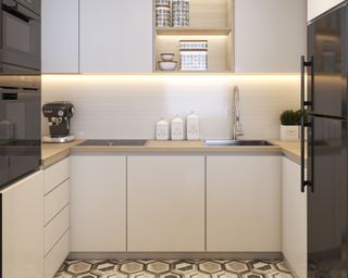 Small white kitchen with lights under cabinets and geometric patterned floor tiles and a black refrigerator