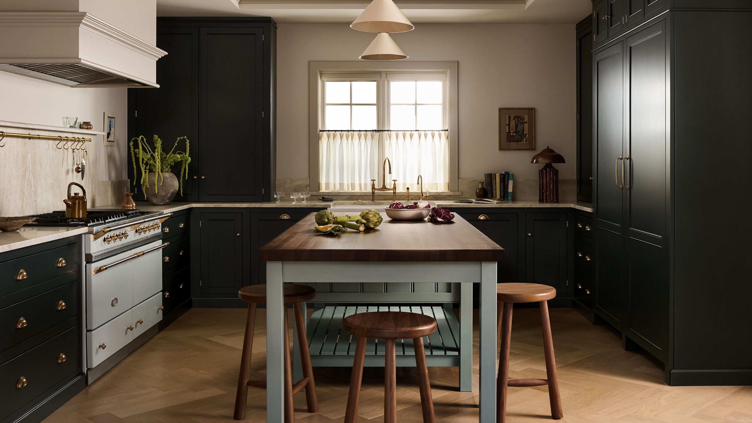 a large open deVOL kitchen with dark cabinetry, a white range cooker, blue island with wooden worktops and a window with cafe curtain