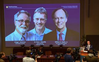 Nobel Assembly member, Randall Johnson, speaks during the announcement of this year’s winners of the Nobel Prize in Physiology or Medicine, at the Karolinska Institute in Sweden: (from left to right on the screen) Gregg Semenza, Peter Ratcliffe and William Kaelin.