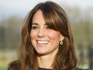 Kate Middleton laughing in a blue and green tartan dress