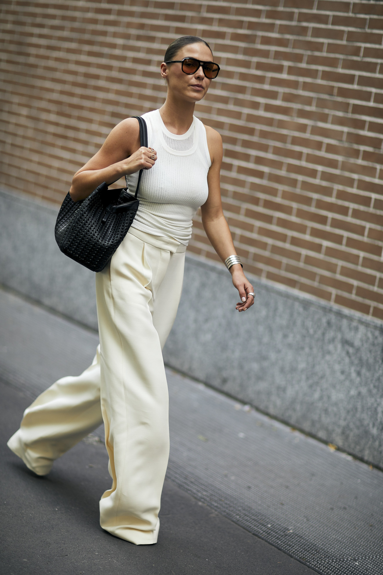 woman wearing white tank top, white trousers, and black tote bag