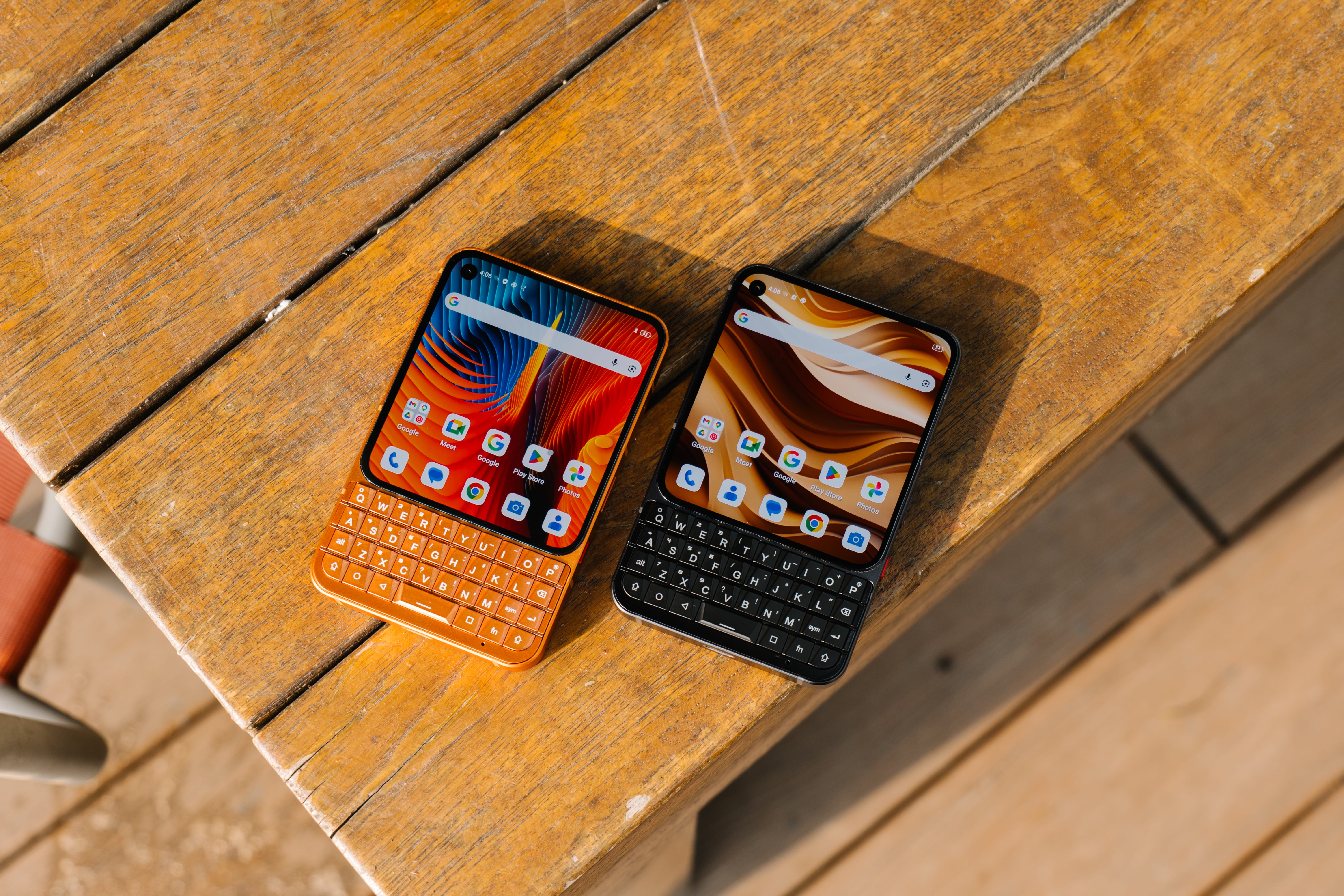 The orange and black models of the Titan 2 Elite are placed together on a wooden slatted table in bright, natural light.