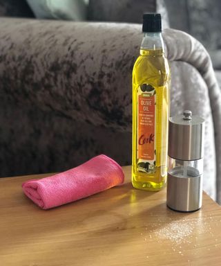 A pink microfiber cloth with bottle of olive oil and rock salt grinder