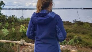 Woman wearing Paramo Velez waterproof jacket, with harbour in the background