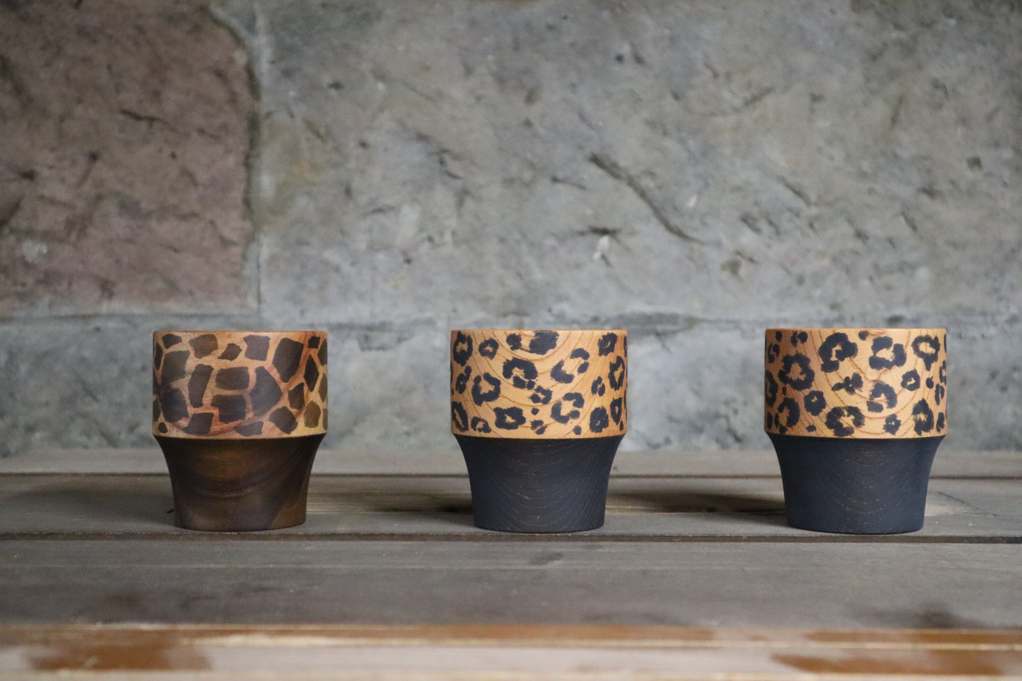 three wooden vessels painted with animal prints in ink