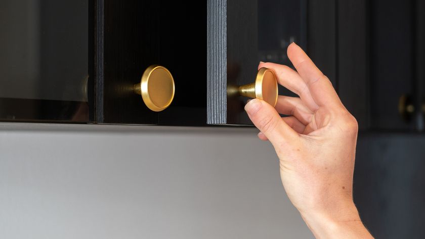 A hand opening a kitchen cupboard