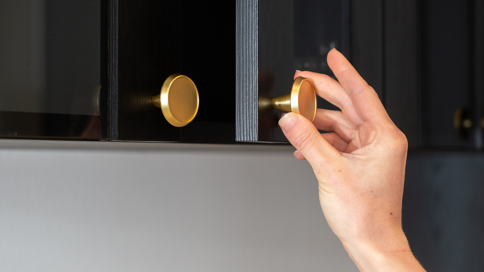 A hand opening a kitchen cupboard